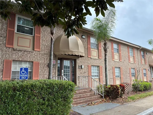 a view of a brick house with a yard and large tree