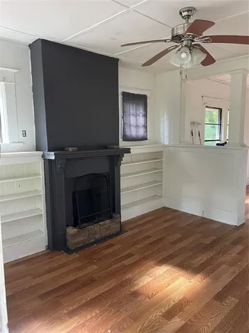a living room with a fireplace windows and a ceiling fan