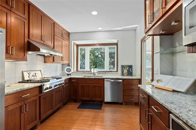 a large kitchen with stainless steel appliances granite countertop a sink stove and cabinets