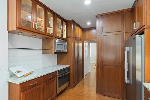 a kitchen with stainless steel appliances granite countertop a refrigerator a stove and a sink with wooden floor