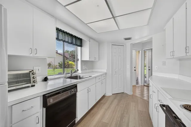 a kitchen with cabinets appliances wooden floor and a window