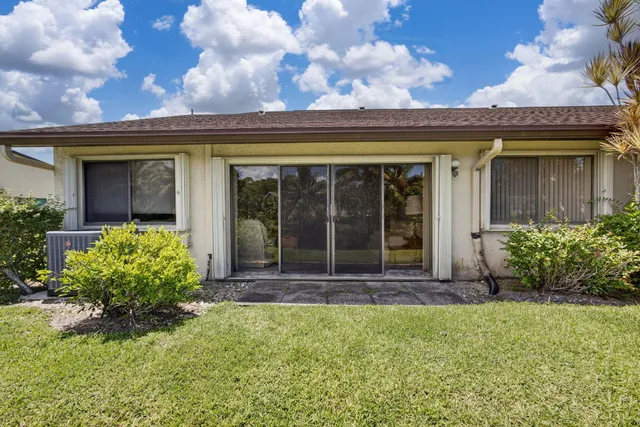 a view of a house with a big yard and palm trees