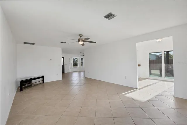 an empty room with windows and ceiling fan