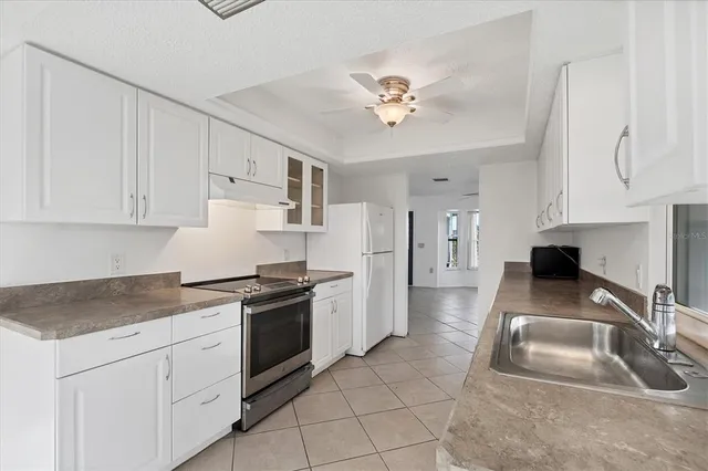 a kitchen with granite countertop a sink stainless steel appliances and white cabinets