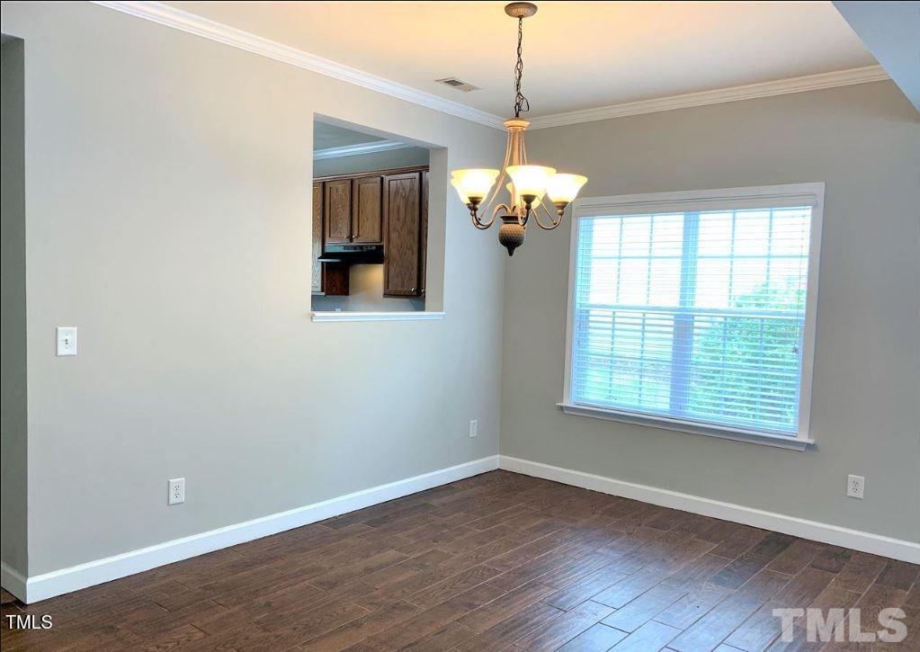 142 Forthview Way Apex, NC 27502 - Photo 5 of 11 an empty room with wooden floor chandelier and windows
