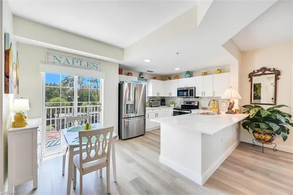 a kitchen with stainless steel appliances a microwave a stove a refrigerator a dining table and chairs