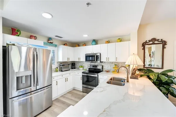 a kitchen with stainless steel appliances granite countertop a refrigerator a stove and a sink