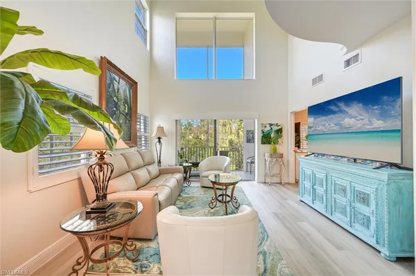 a living room with furniture a flat screen tv and a floor to ceiling window