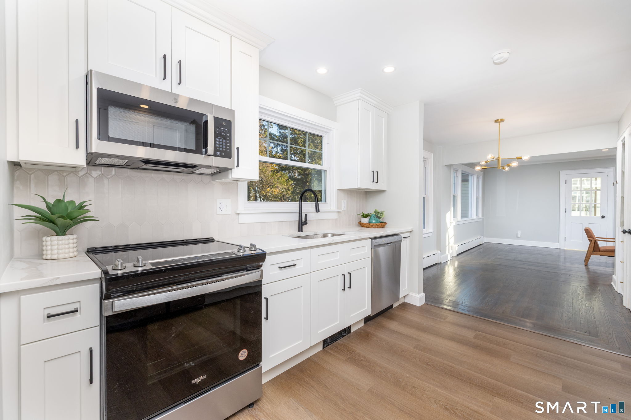 a kitchen with granite countertop a stove a microwave a sink a refrigerator and white cabinets