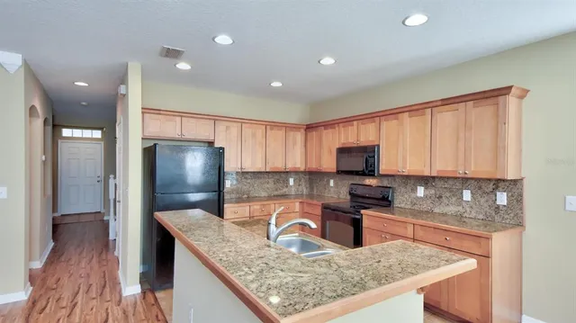 a kitchen with granite countertop a refrigerator a stove and a sink