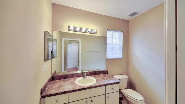 a bathroom with a granite countertop sink toilet and mirror