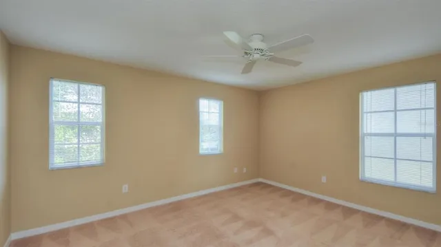 an empty room with windows and fan