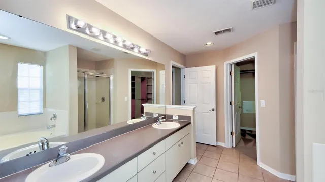a spacious bathroom with a double vanity sink a mirror and a shower