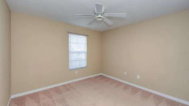 an empty room with a window and a fan