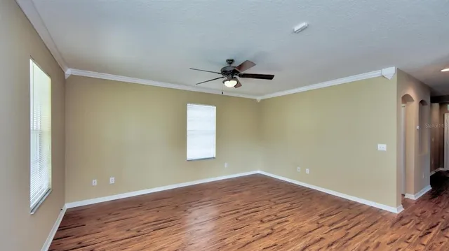 a view of an empty room with a window and wooden floor