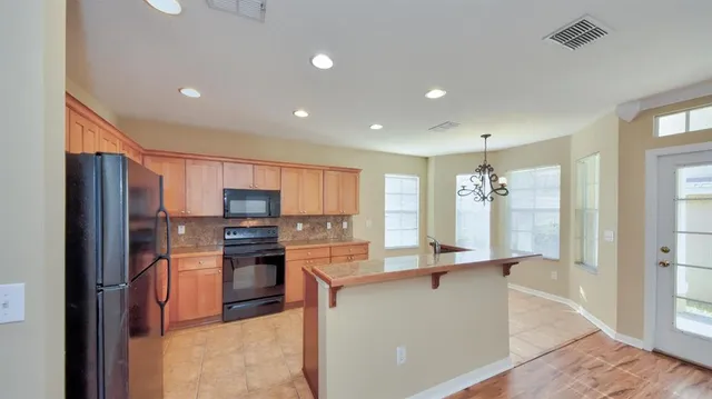 a kitchen with stainless steel appliances kitchen island granite countertop a refrigerator stove and sink