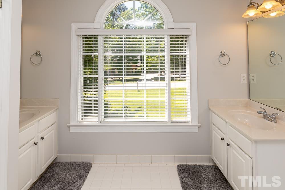 12625 Amoretto Way Raleigh, NC 27613 - Photo 29 of 42 a bathroom with a granite countertop sink a large mirror and a bathtub next to a window