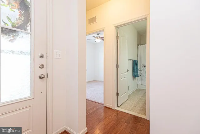 an empty room with chandelier fan and windows
