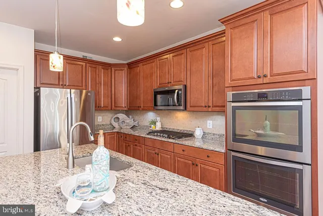 a kitchen with granite countertop a refrigerator stove top oven and sink