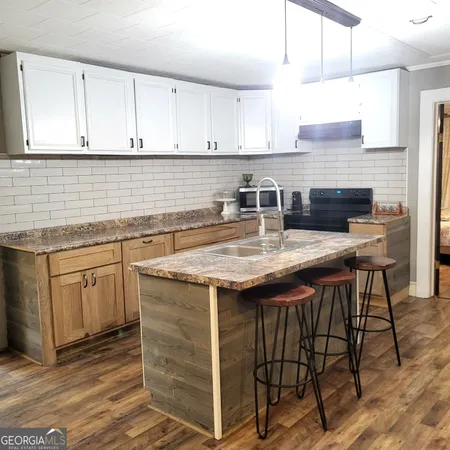 a kitchen with granite countertop a sink a stove and cabinets
