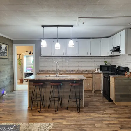 a kitchen with kitchen island granite countertop a stove top oven a sink and cabinets