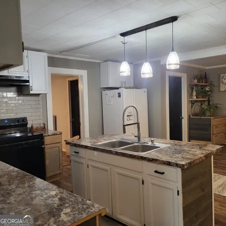 a kitchen with kitchen island granite countertop a sink a stove and refrigerator