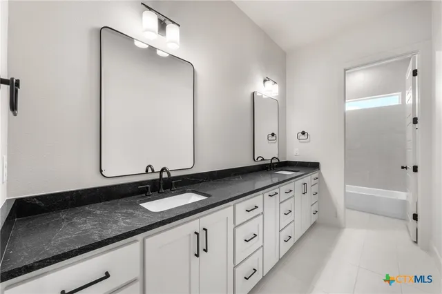 a bathroom with a granite countertop double vanity sink and a mirror