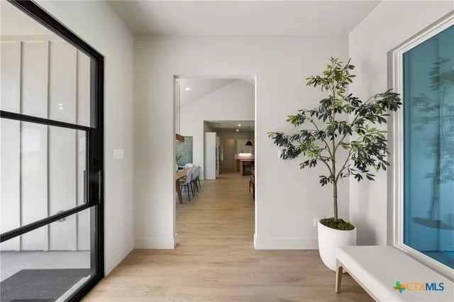a view of a hallway and an entryway with wooden floor