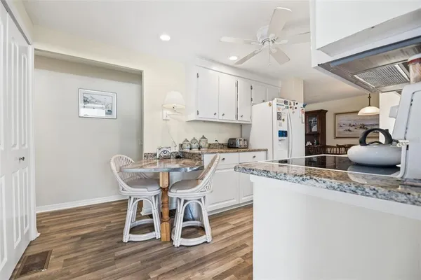 a dining room with stainless steel appliances kitchen island granite countertop a table chairs and a refrigerator