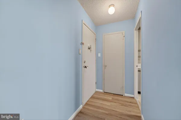 a view of a hallway with wooden floor and a bathroom