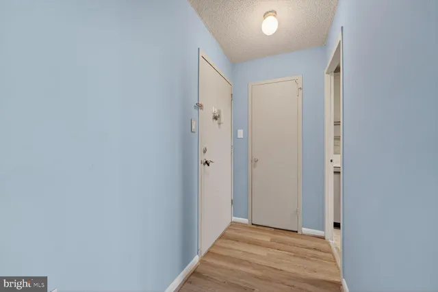 a view of a hallway with wooden floor and a bathroom