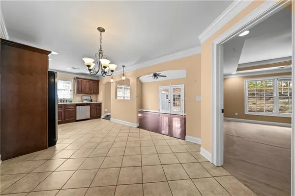 a view of an empty room with chandelier and door