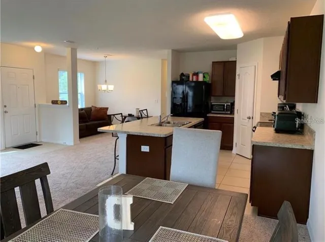 a living room with stainless steel appliances furniture a rug a fireplace and a flat screen tv