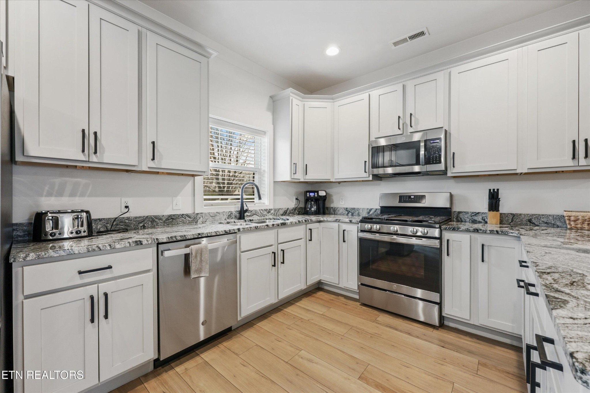 418 Fleeta Williams Way Sevierville, TN 37862 - Photo 10 of 39 a kitchen with stainless steel appliances granite countertop a stove a sink and white cabinets