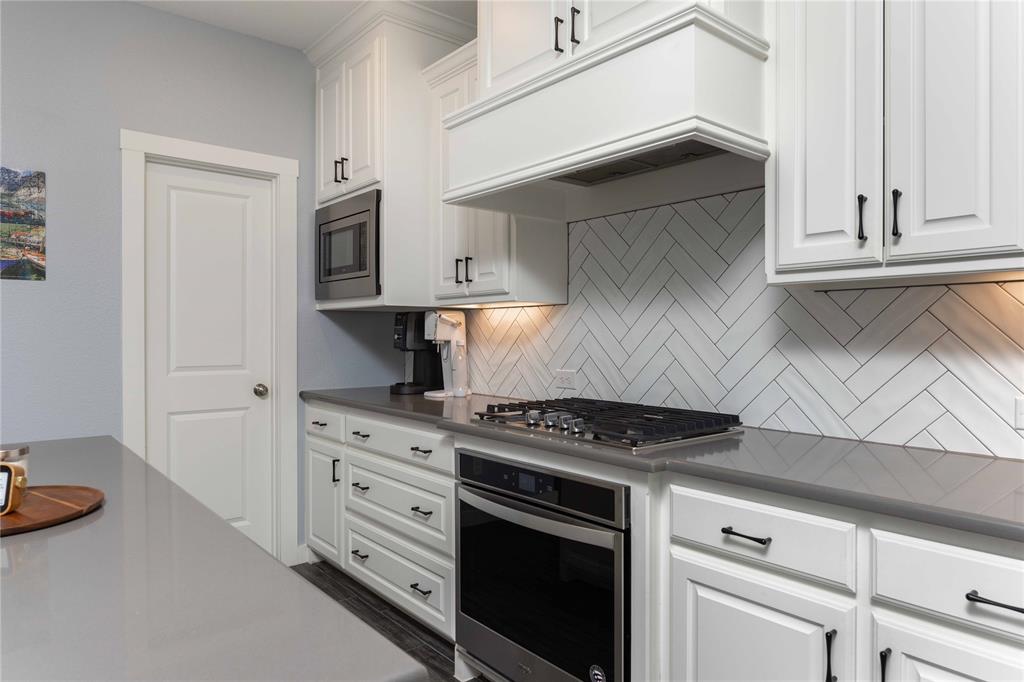 631 Cobblestone Lane Irving, TX 75039 - Photo 8 of 32 a kitchen with white cabinets and a stove with wooden floor