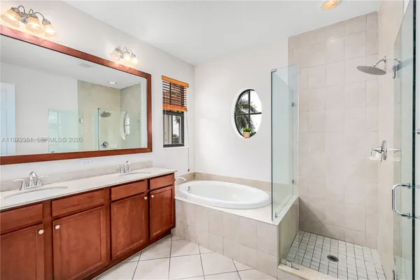 a bathroom with a bathtub shower sink vanity and mirror