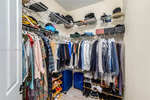 a view of walk in closet with clothes and shoes