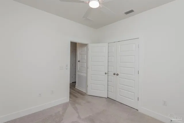 an empty room with closet and a chandelier fan