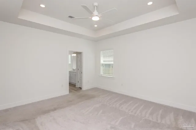 an empty room with chandelier fan and windows