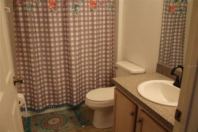 a bathroom with a granite countertop toilet and a sink