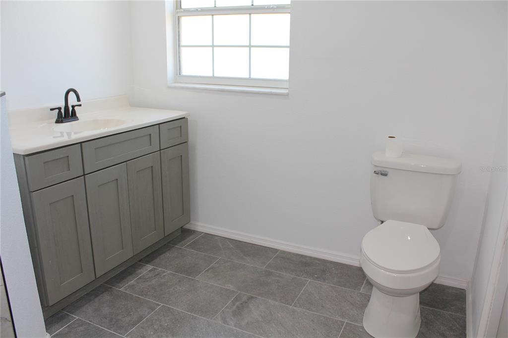 7238 Evergreen Loop Polk City, FL 33868 - Photo 19 of 28 a bathroom with a toilet a sink a window and mirror