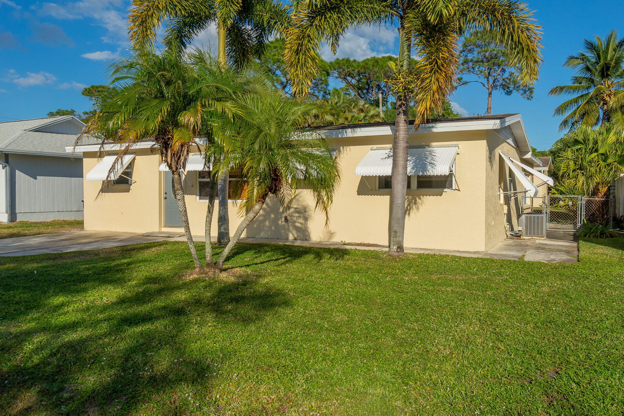 5519 Southeast Normandy Avenue Stuart, FL 34997 - Photo 2 of 38 a view of a white house with a yard and palm trees