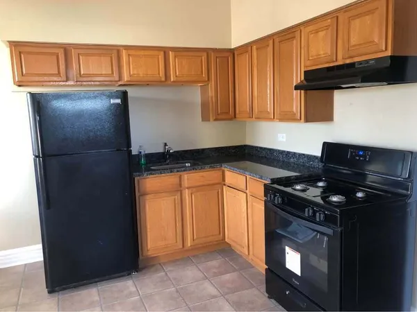 a kitchen with granite countertop a stove top oven cabinetry and refrigerator