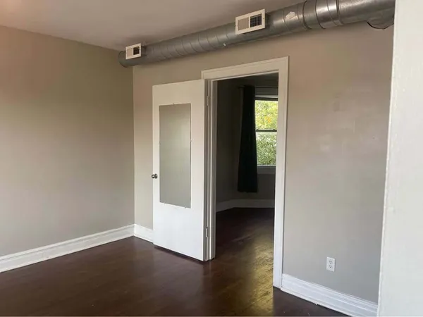 an empty room with wooden floor closet and windows