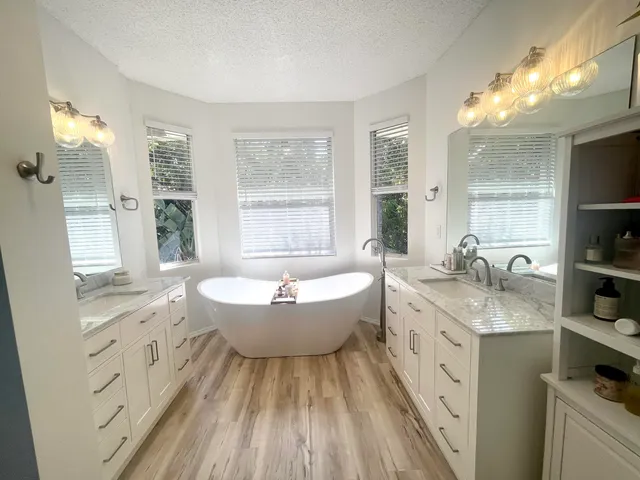 a spacious bathroom with double vanity a granite countertop a sink a toilet a mirror and shower