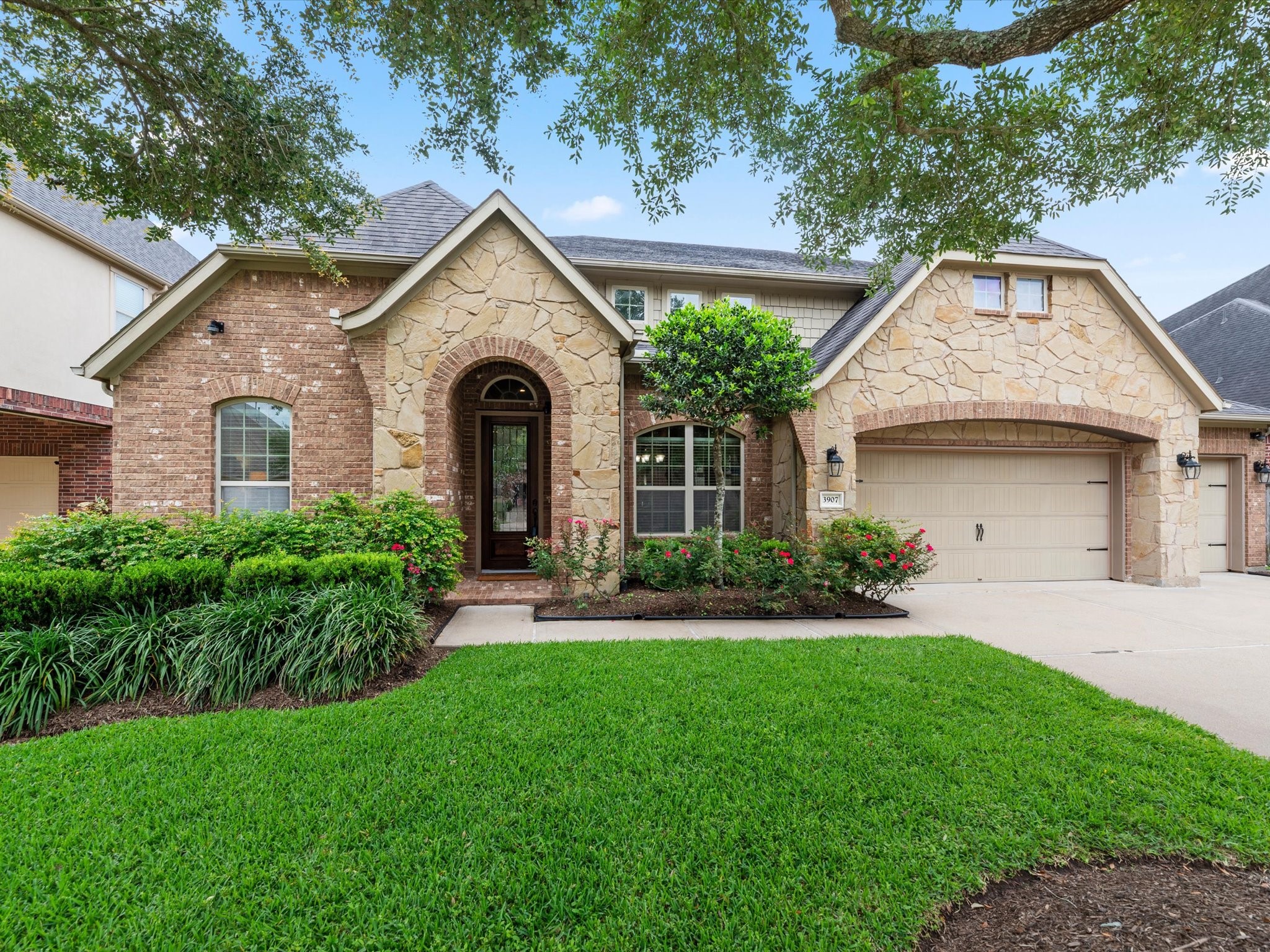 3907 Randle Ridge Court Fulshear, TX 77441 - Photo 1 of 46 Charming single-story home with a stone and brick exterior, featuring an inviting arched entryway. The well-maintained front yard includes lush landscaping and mature trees, enhancing curb appeal. A spacious driveway leads to a three-car garage.