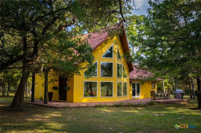 a view of a building with a big yard and large trees