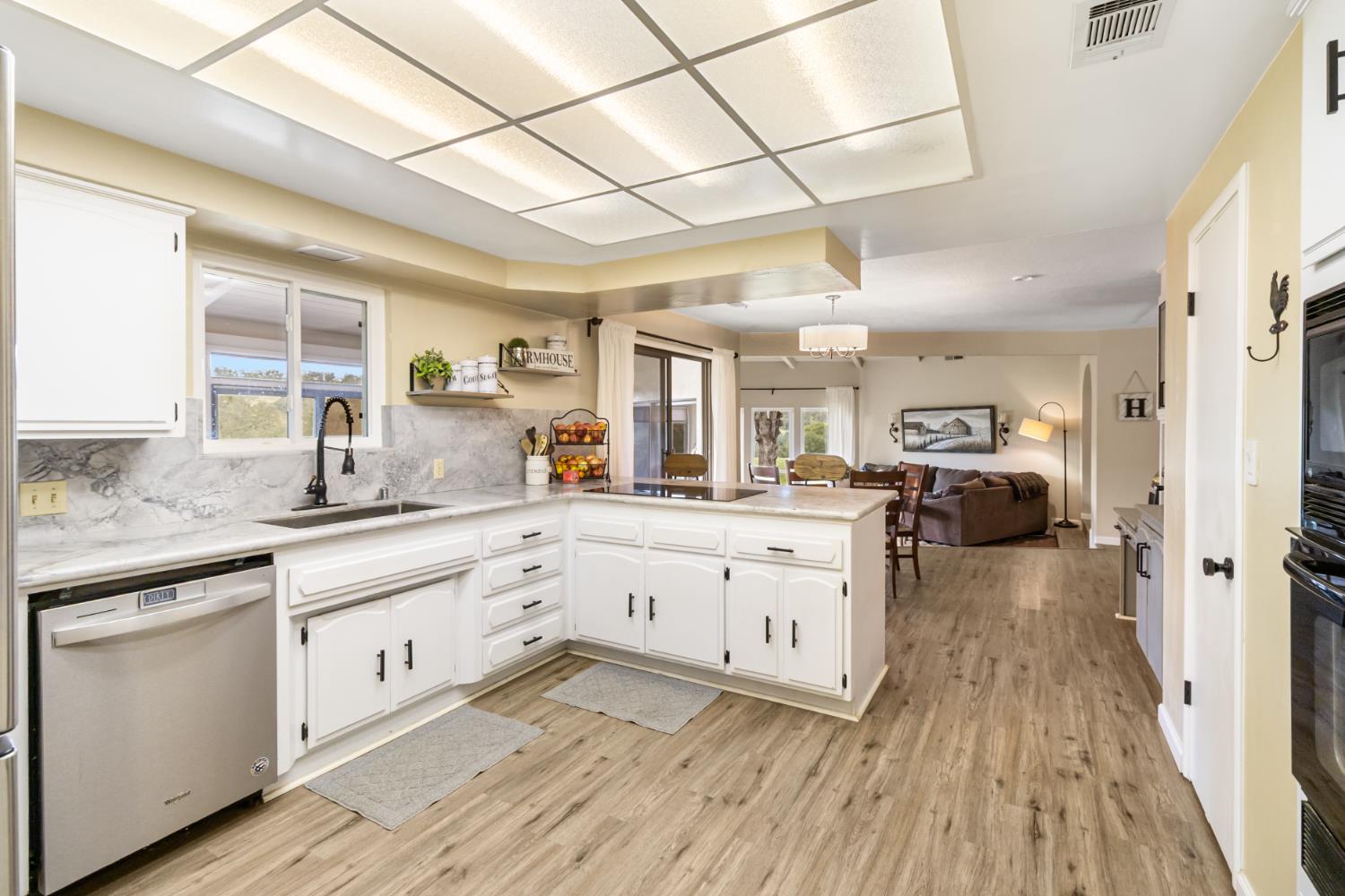 22800 Latrobe Road Plymouth, CA 95669 - Photo 24 of 81 a large white kitchen with cabinets a sink dishwasher and a stove with wooden floor