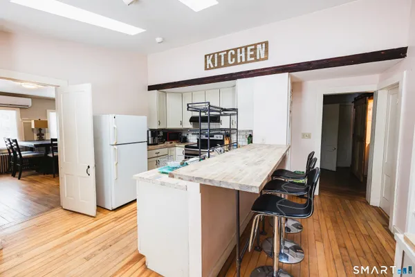 a kitchen with stainless steel appliances granite countertop a refrigerator a stove and a wooden floor