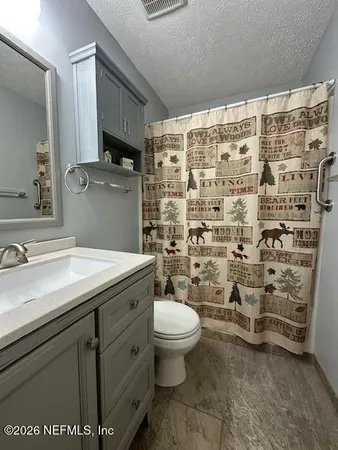 a bathroom with a granite countertop sink a toilet and a shower